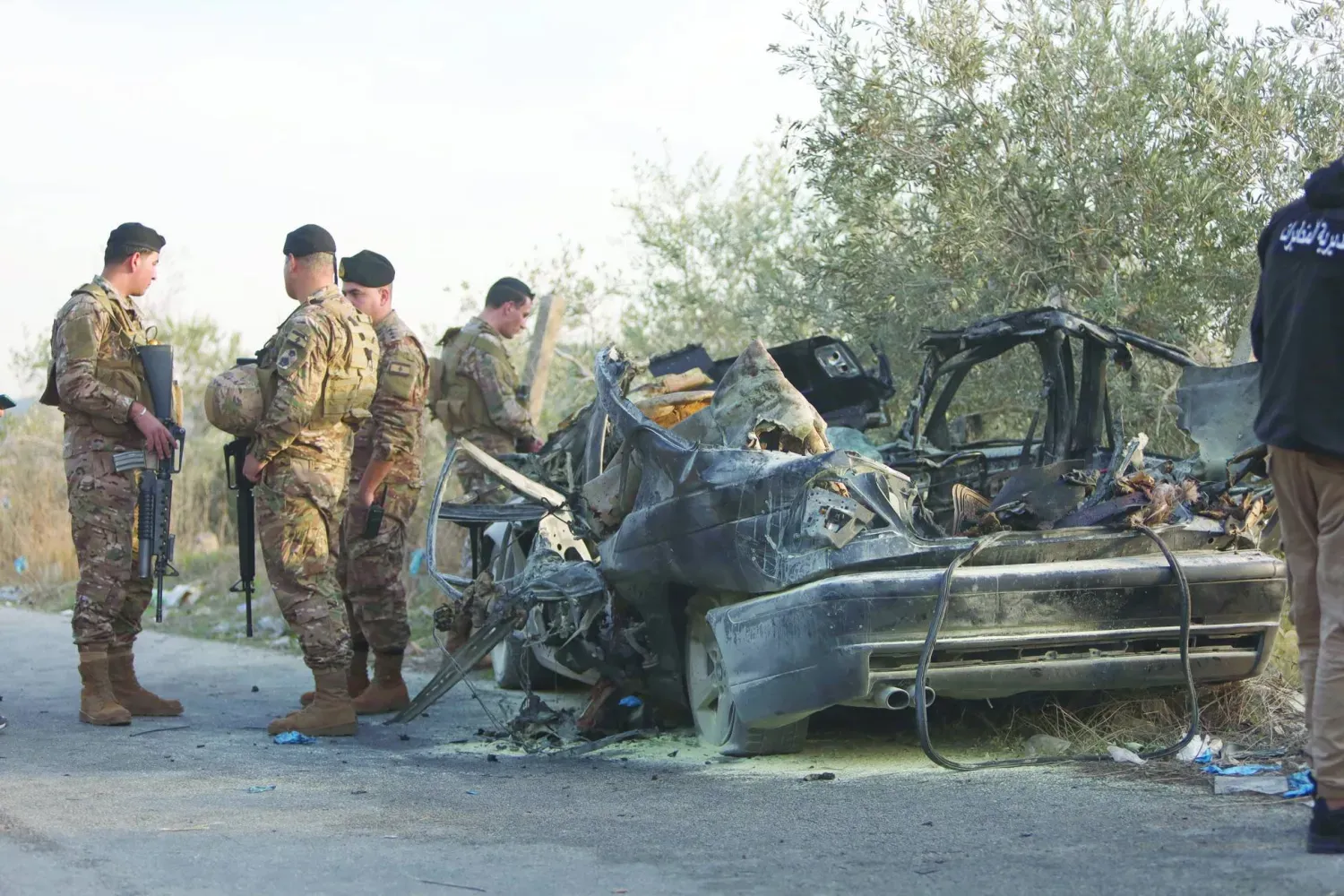 İsrail’in Lübnan'ın güneyindeki Aknit beldesinde hedef aldığı ve üç kişinin hayatını kaybettiği bir aracın yanında duran Lübnan askerleri (DPA)