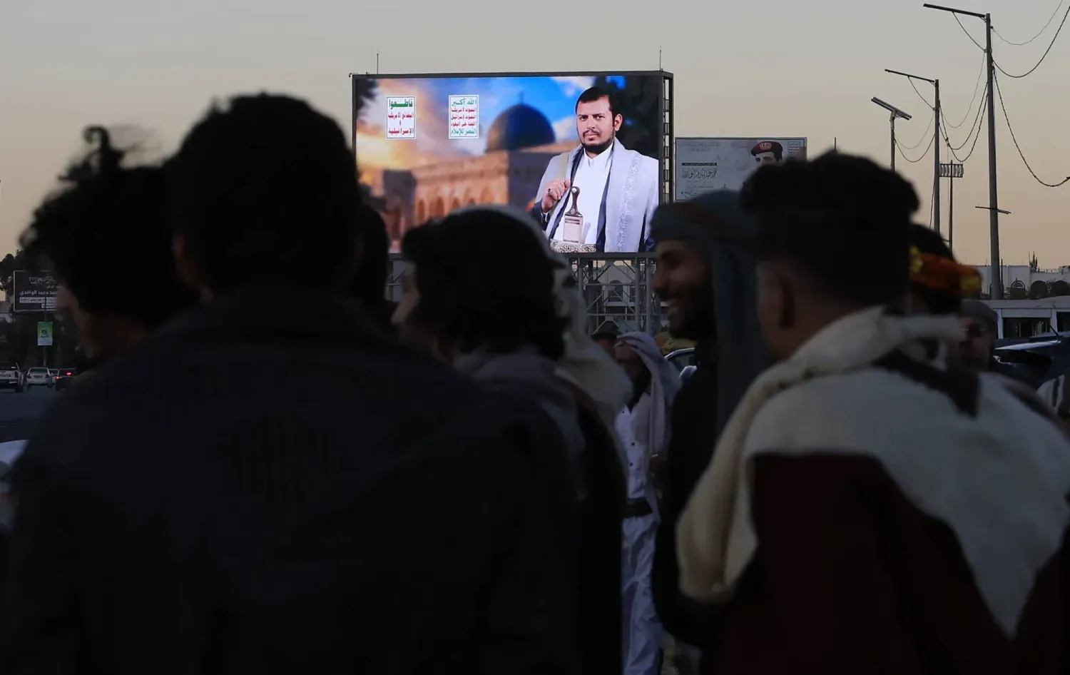 Sana'da Husi liderinin fotoğrafının bulunduğu bir dijital reklam panosunun önünde toplanan insanlar (EPA)