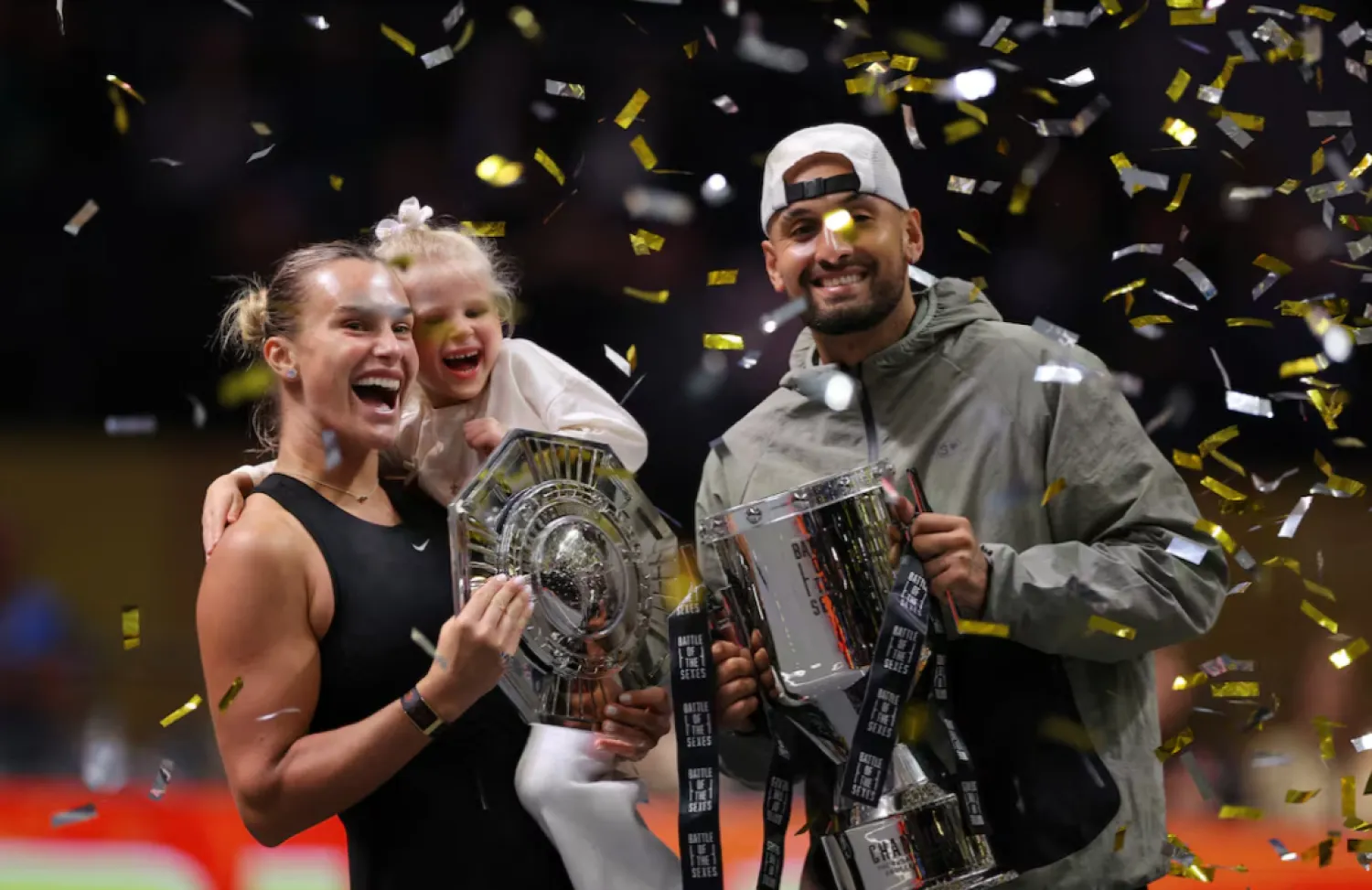  Tennis - 'Battle of the Sexes' - Nick Kyrgios v Aryna Sabalenka - Coca-Cola Arena, Dubai, United Arab Emirates - December 28, 2025 Belarus' Aryna Sabalenka, her goddaughter Nicole, and Australia's Nick Kyrgios celebrate with trophies after the match REUTERS/Amr Alfiky/Pool 