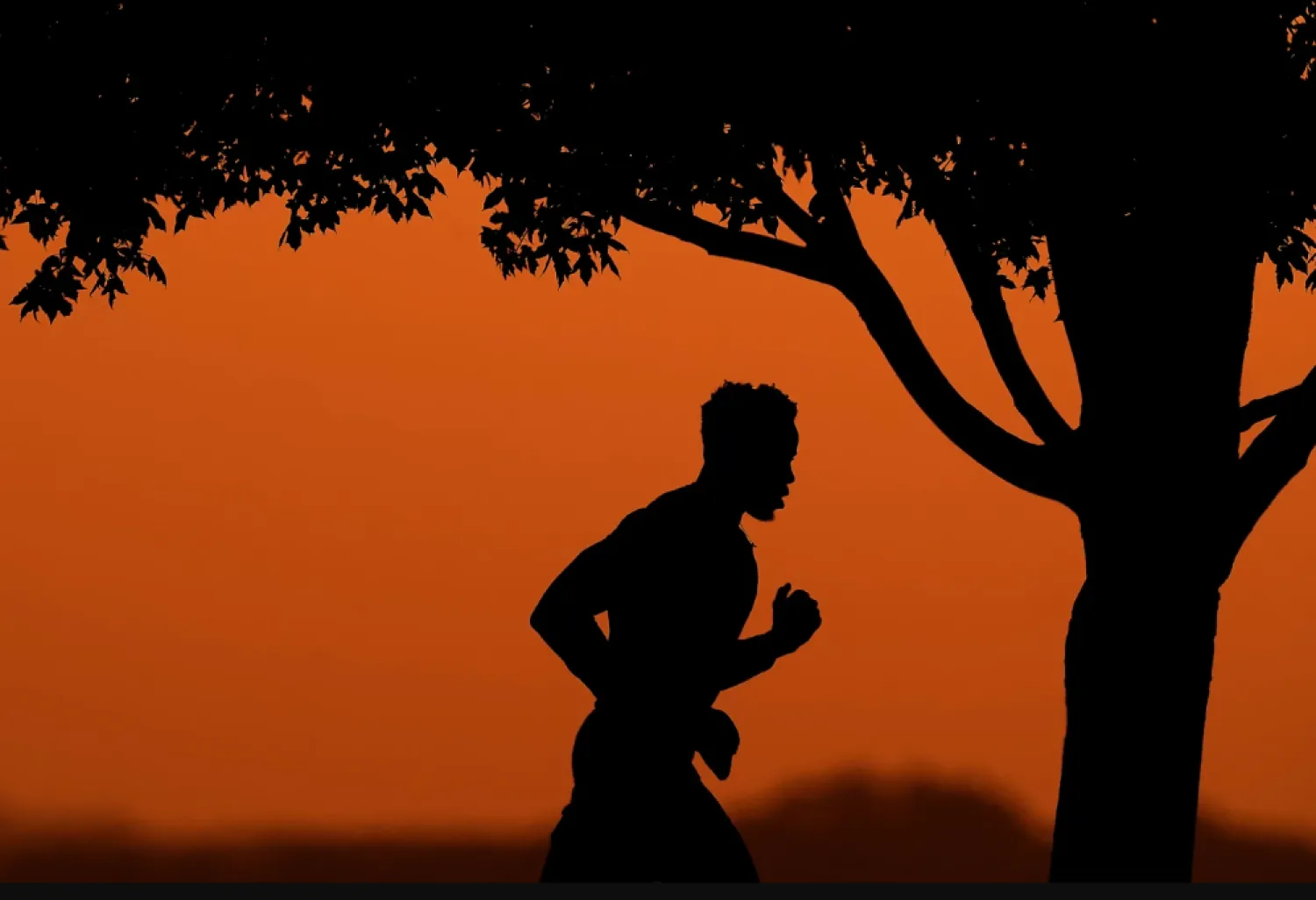 A man is silhouetted against the sky at sunset as he jogs in a park at the close of a hot summer day, Aug. 1, 2022, in Kansas City, Mo. (AP Photo/Charlie Riedel, File)