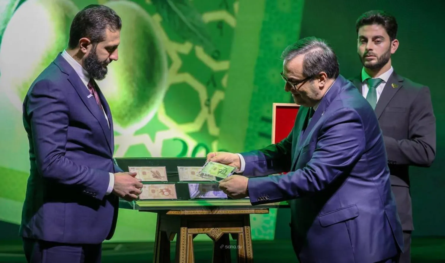 الرئيس السوري وحاكم المصرف المركزي خلال إطلاق العملة الجديدة (سانا)