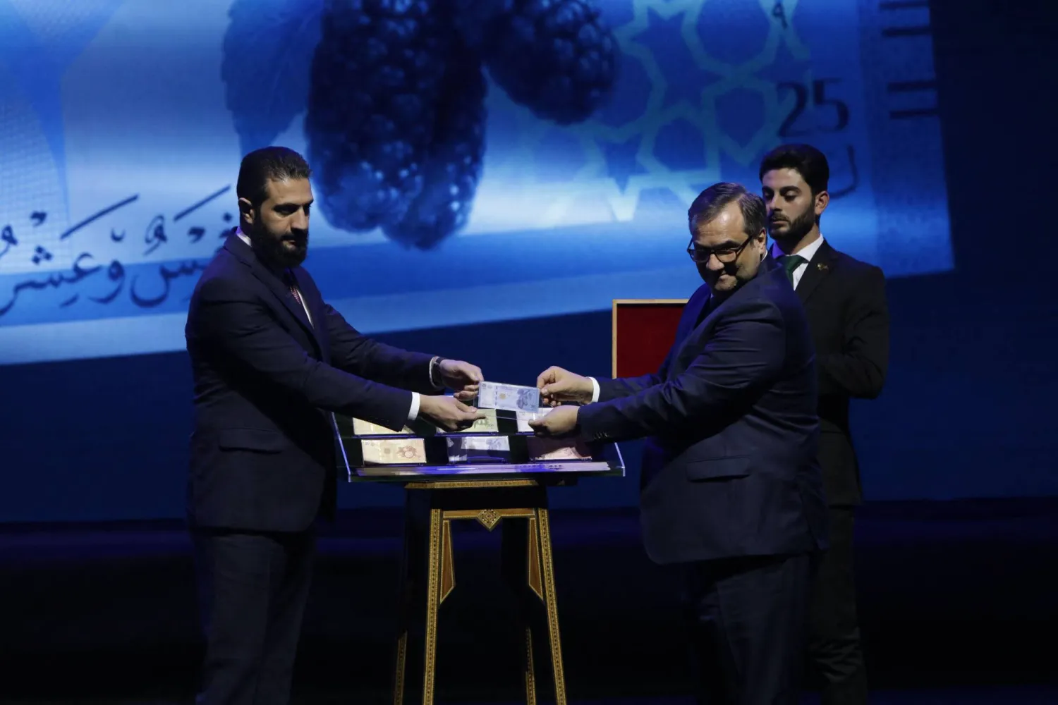 Syria's President Ahmed al-Sharaa (L) and Syria's Central bank chief Abdul Qadir al-Hasriya (R) hold one of the country's new revamped currency notes at the Conference Palace in the Syrian capital Damascus on December 29, 2025. (AFP)