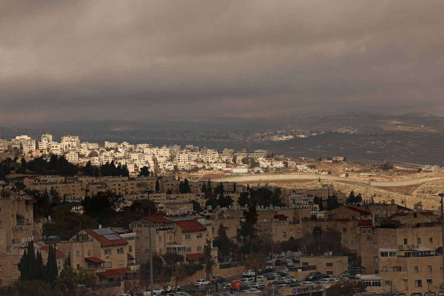 This picture shows the Israeli settlement of Pisgat Zeev, (foreground) in the northern area of East Jerusalem and Israel's controversial barrier separating the Palestinian neighborhood of al-Ram (background) in the occupied West Bank on December 27, 2025 (AFP)