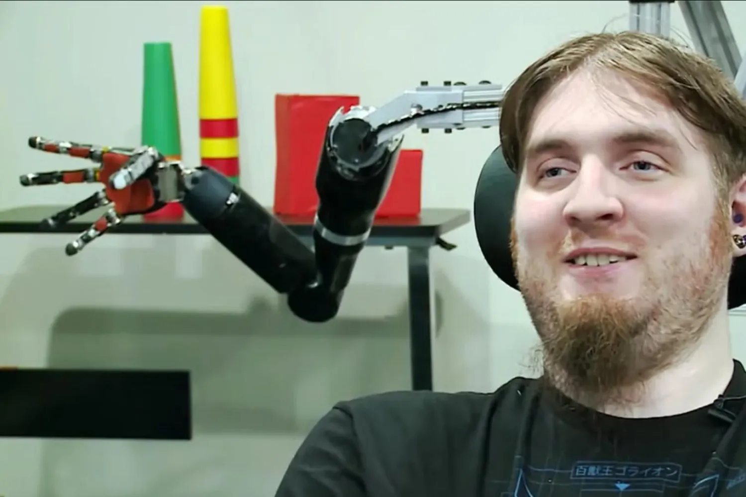 Beyin bilgisayar arayüzü öncüsü Nathan Copeland, 2019'da bir robotik kolun önünde (Pittsburgh Üniversitesi Tıp Merkezi)