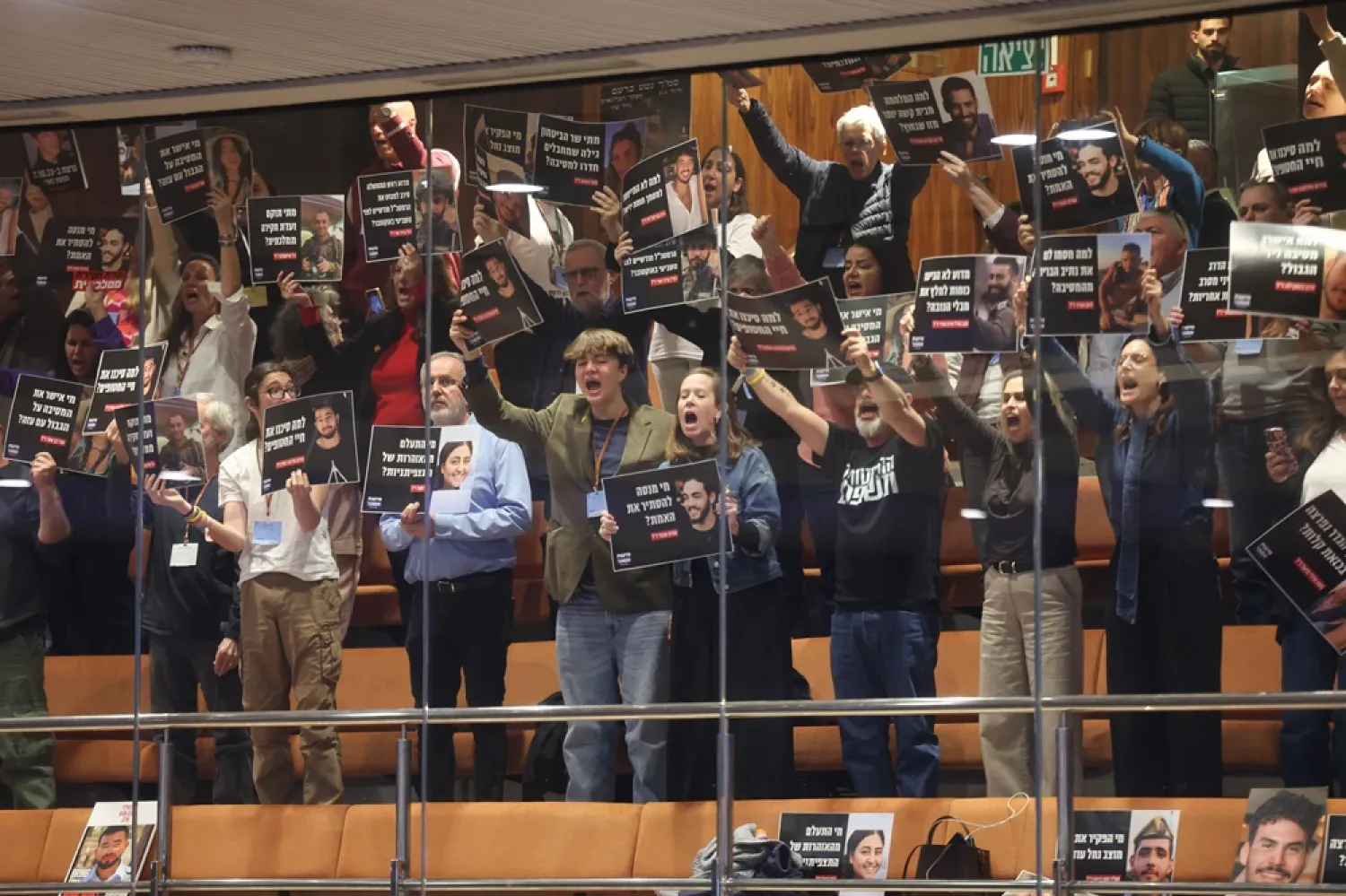The bereaved families of the 7 October attack hold pictures of their loved ones and shout slogans towards Knesset members during a debate on the bill for a state commission of inquiry into the events of 7 October at the Knesset, the Israeli parliament, in Jerusalem, 24 December 2025. (EPA) 