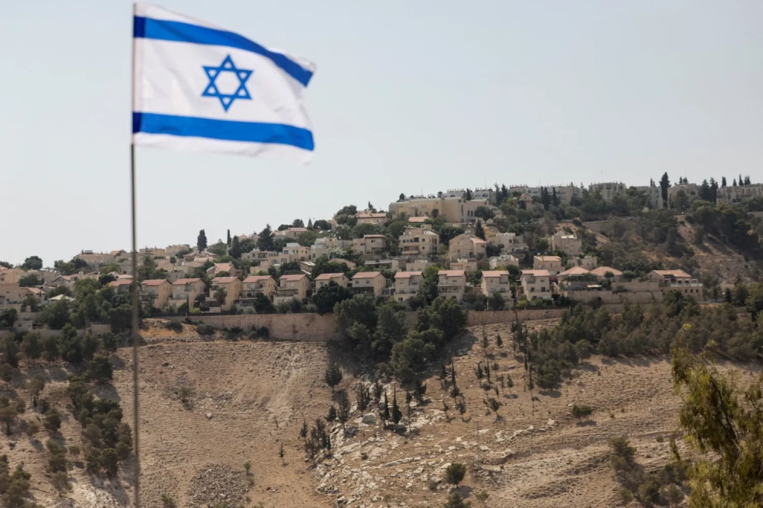 An Israeli flag flutters, as part of the Israeli settlement of Maale Adumim is visible in the background, in the Israeli-occupied West Bank, August 14, 2025. (Reuters) 