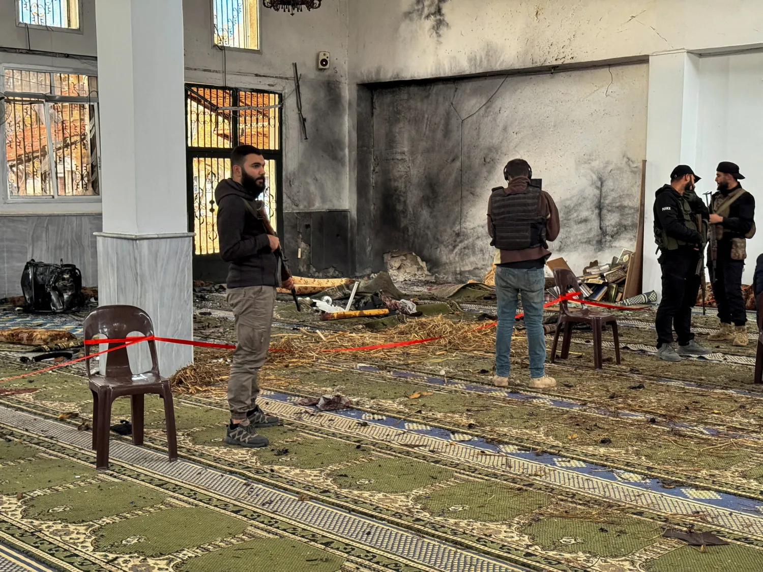Syrian security forces stand inside a damaged mosque after several people were killed in an explosion at a mosque as the Syrian Arab News Agency (SANA) said, in Homs, Syria December 26, 2025. REUTERS/Ali Ahmed al-Najjar 