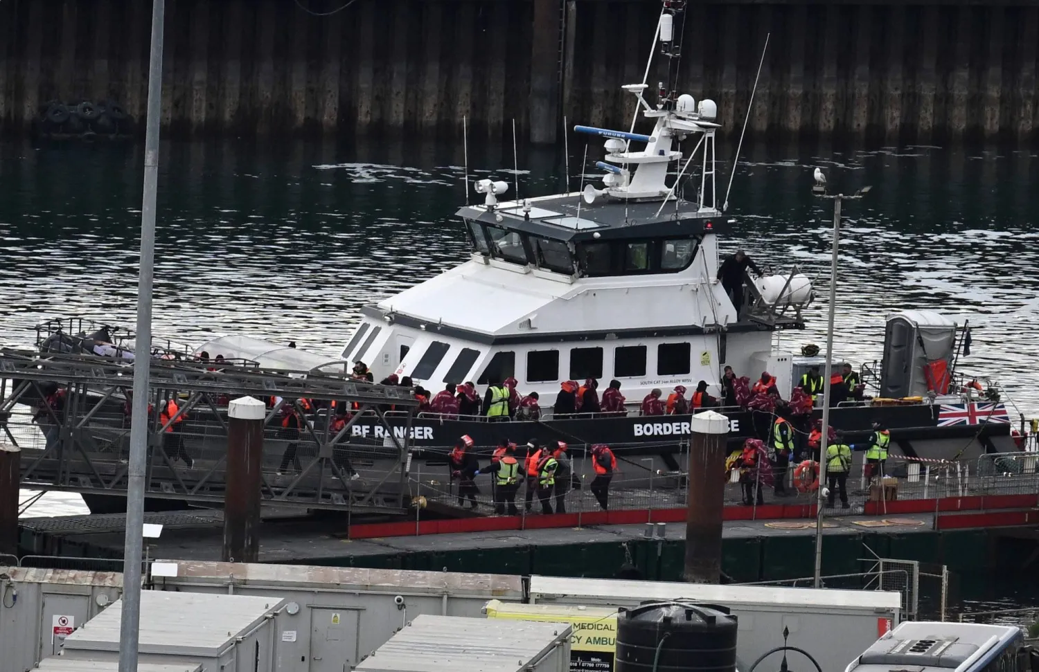 (FILES) Migrants picked up at sea attempting to cross the English Channel from France, disembark from Border Force vessel 'Ranger' after it arrived at the Marina in Dover, south-east England, on May 21, 2025. (Photo by Ben STANSALL / AFP)