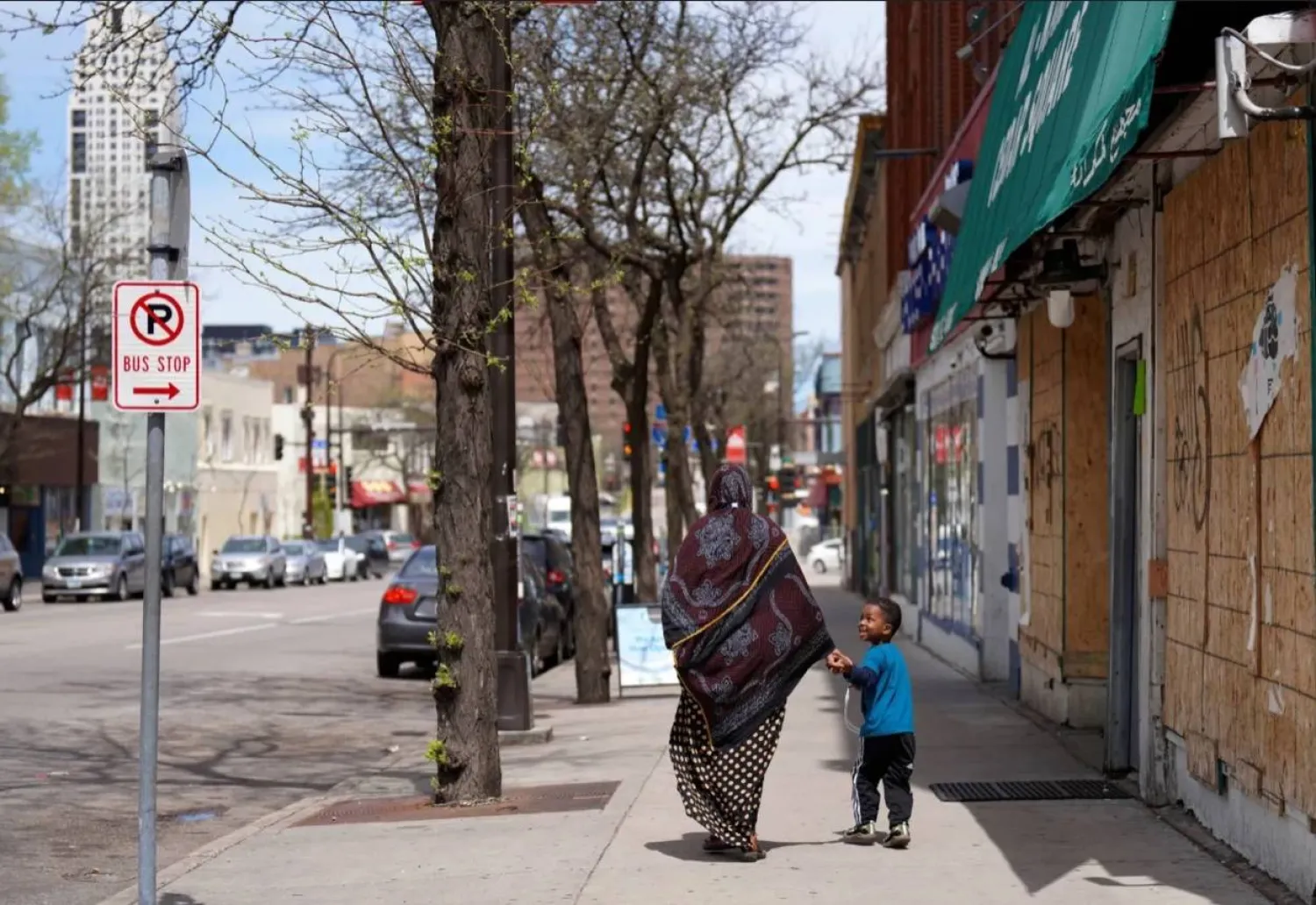 A woman and a child hold hands as they walk down a street in the predominantly Somali neighborhood of Cedar-Riverside in Minneapolis in May 2022. Jessie Wardarski/AP
