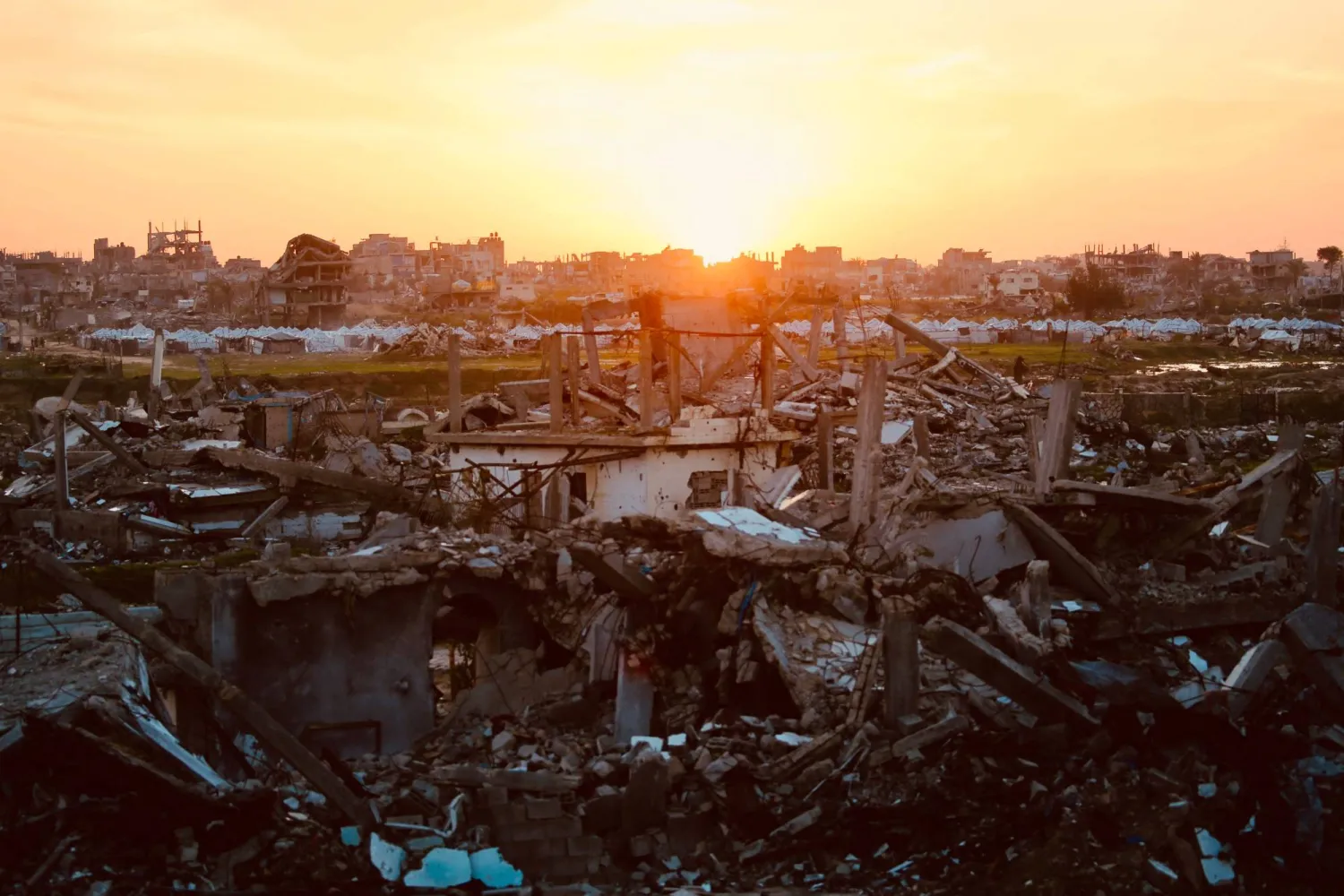 The sun sets behind the ruins of destroyed buildings in the Nuseirat refugee camp in the central Gaza Strip on December 31, 2025. (AFP)