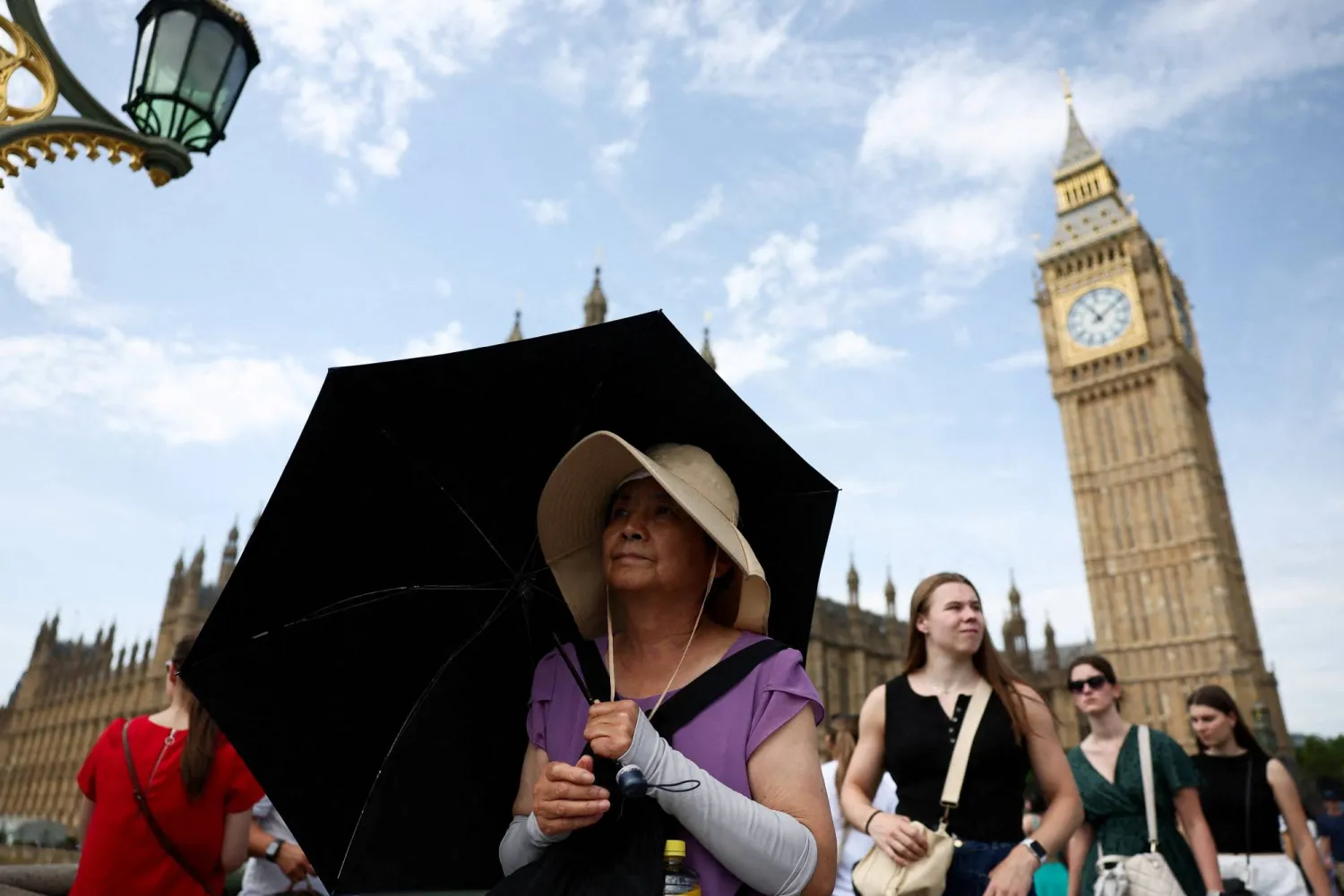 FILE PHOTO: A woman shields herself from sun with an umbrella at Westminster Bridge in London, Britain, June 21, 2025. REUTERS/Isabel Infantes/File Photo