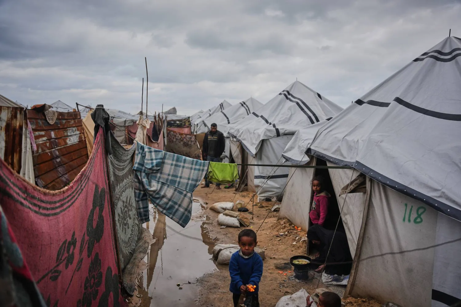 Nanaa Abu Jari cooks outside her tent after it was flooded by rainwater in Nuseirat, central Gaza Strip, Friday, Jan. 2, 2026. (AP Photo/Abdel Kareem Hana)
