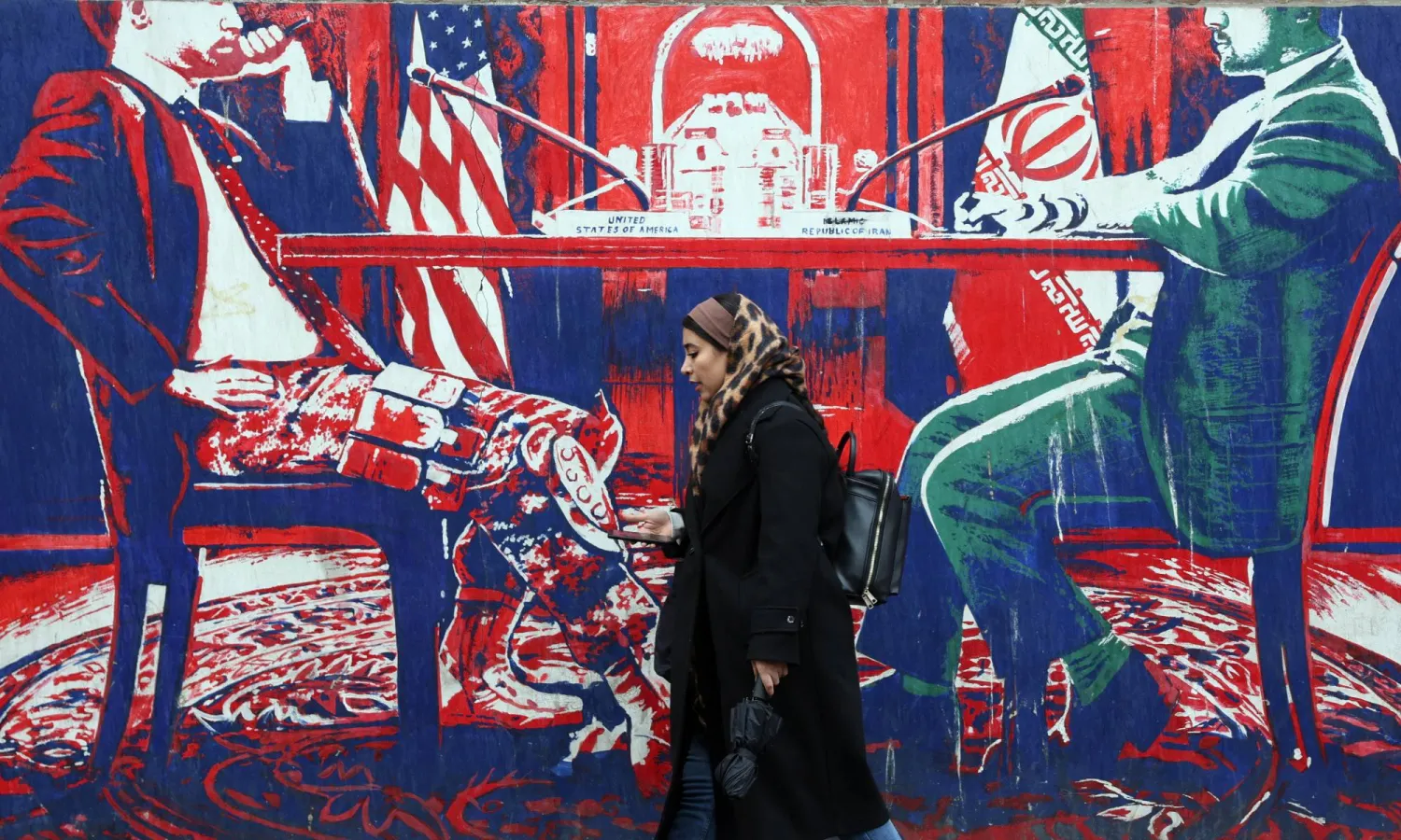 An Iranian woman walks past an anti-US mural on a street in Tehran, Iran, 03 January 2026. EPA/ABEDIN TAHERKENAREH