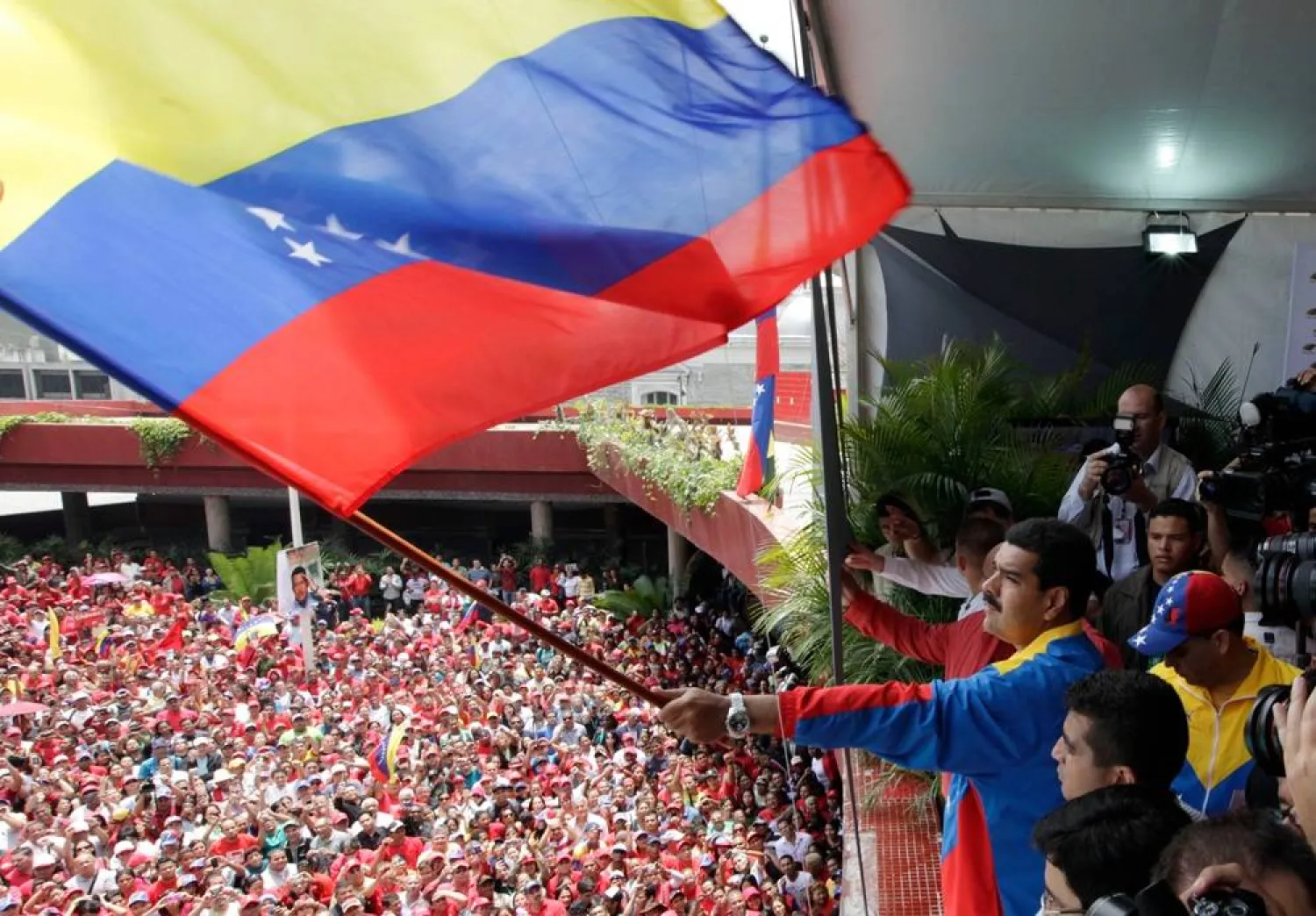 Venezuela's acting President Nicolas Maduro waves a national flag over supporters after registering his candidacy for president to replace late President Hugo Chavez at the national electoral council in Caracas, Venezuela, March 11, 2013. (AP Photo/Ariana Cubillos, File) 