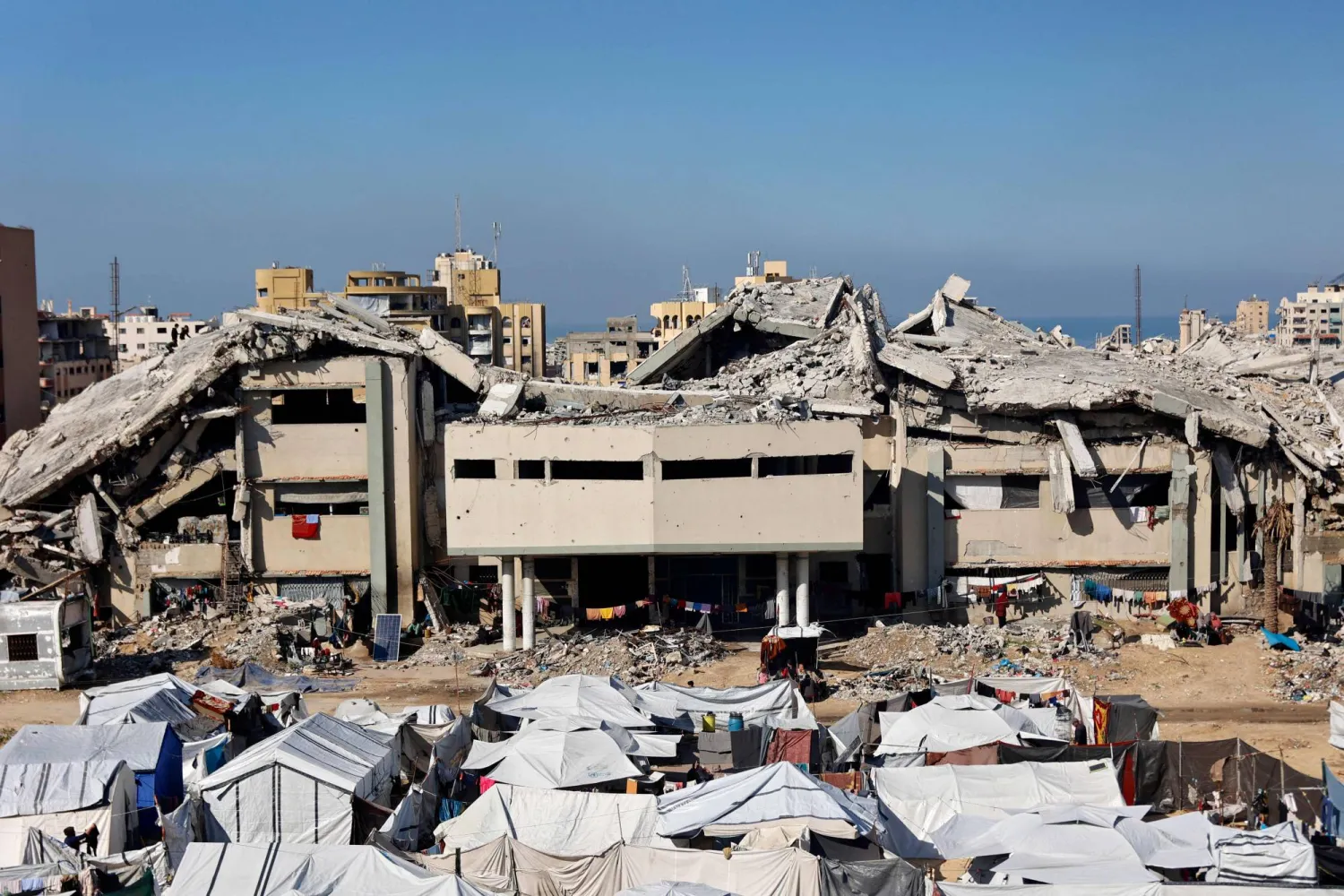 تجمُّع لخيام النازحين الفلسطينيين أمام المباني المدمَّرة للجامعة الإسلامية في مدينة غزة (أ.ف.ب)