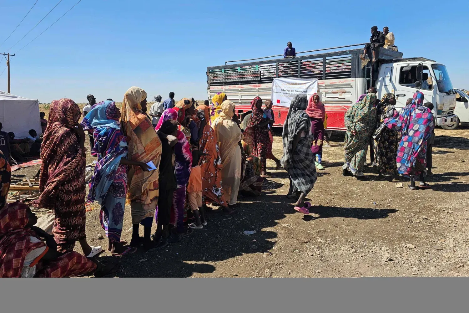 30 Aralık 2025'te Hartum'un kuzeyindeki bir kampta savaştan kaçan Sudanlılar insani yardım almak için bekliyor (AFP)