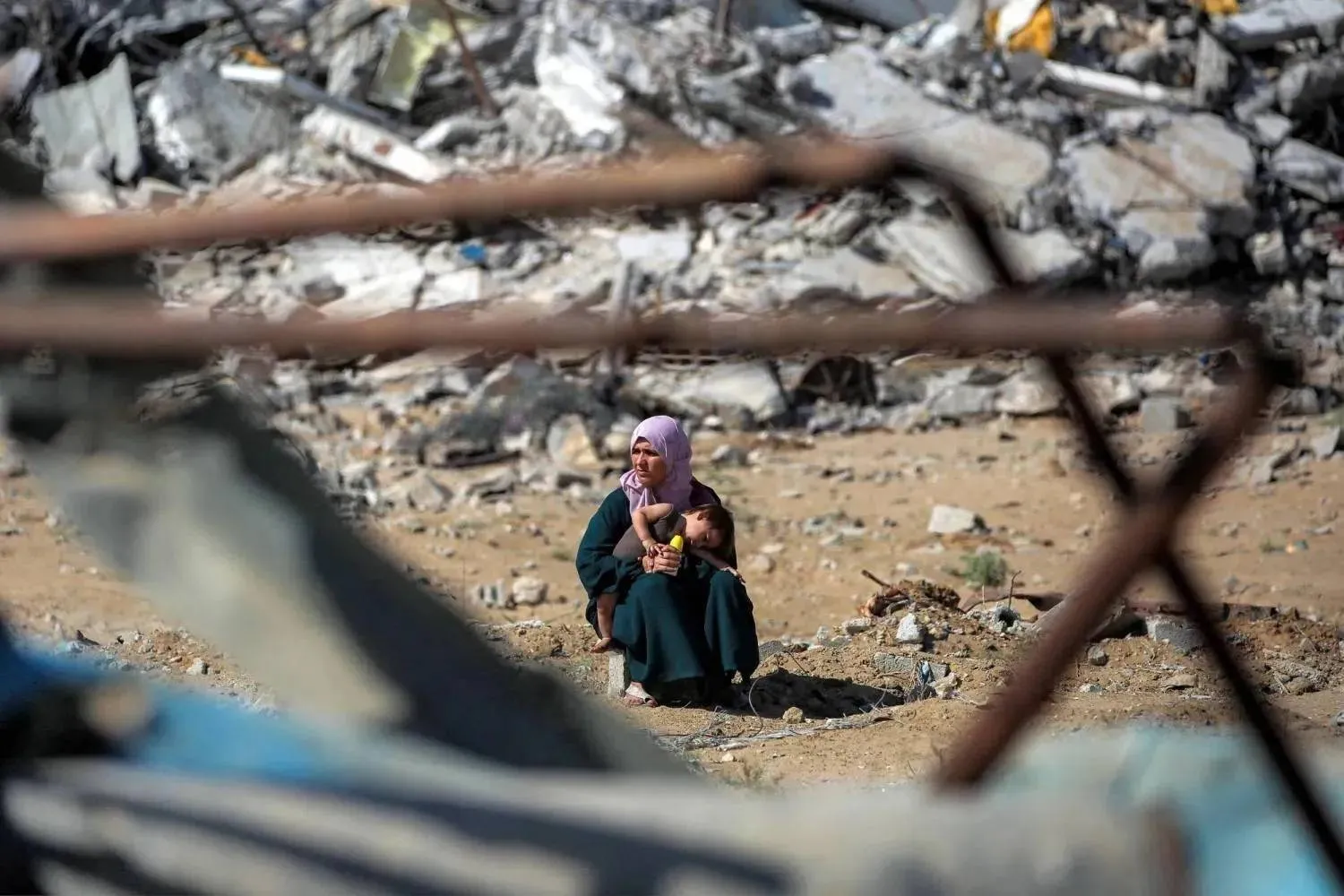 A Palestinian woman holds her child beside piles of rubble while heading toward Gaza City on Friday. (AFP)