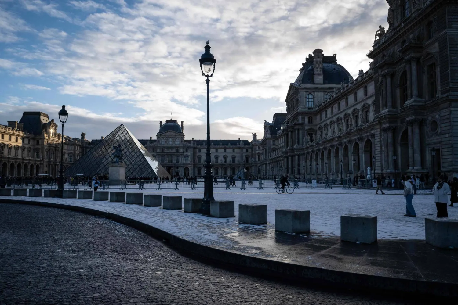 This photograph shows a general view of the Louvre Museum, with the Louvre pyramid (L) designed by Chinese-US architect Ieoh Ming Pei, after the first snowfall of the year in Paris on January 3, 2026. (Photo by Blanca CRUZ / AFP) 