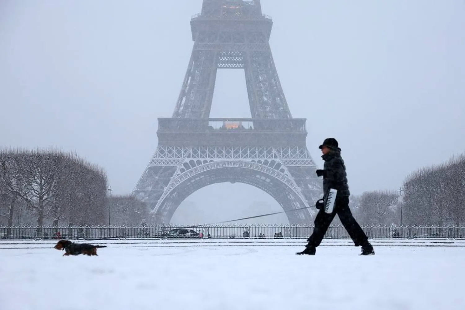 A woman walks her dog in a snow-covered area in front the Eiffel Tower in Paris, as winter weather with snow and cold temperatures hits a large part of the country, France, January 5, 2026. (Reuters) 