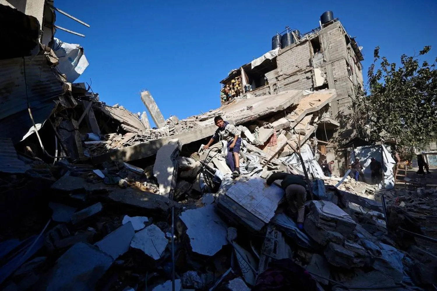 A Palestinian boy looks for his belongings amid the debris of a collapsed house that was previously damaged by an Israeli strike, at the Maghazi refugee camp in the central of Gaza Strip on January 5, 2026. (AFP)