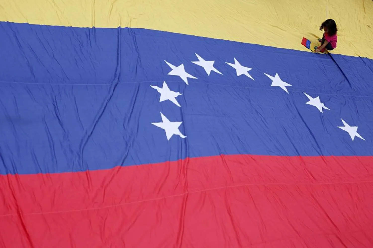 A young protester sits on a large-scale Venezuelan national flag during a protest following US military action in Venezuela, in Rio de Janeiro, Brazil, 05 January 2026. (EPA) 