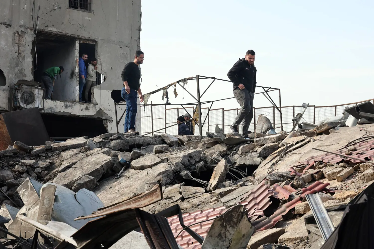 مواطنون يعاينون المبنى الذي استهدف فجراً بغارة إسرائيلية في الغازية قرب مدينة صيدا (إ.ب.أ)