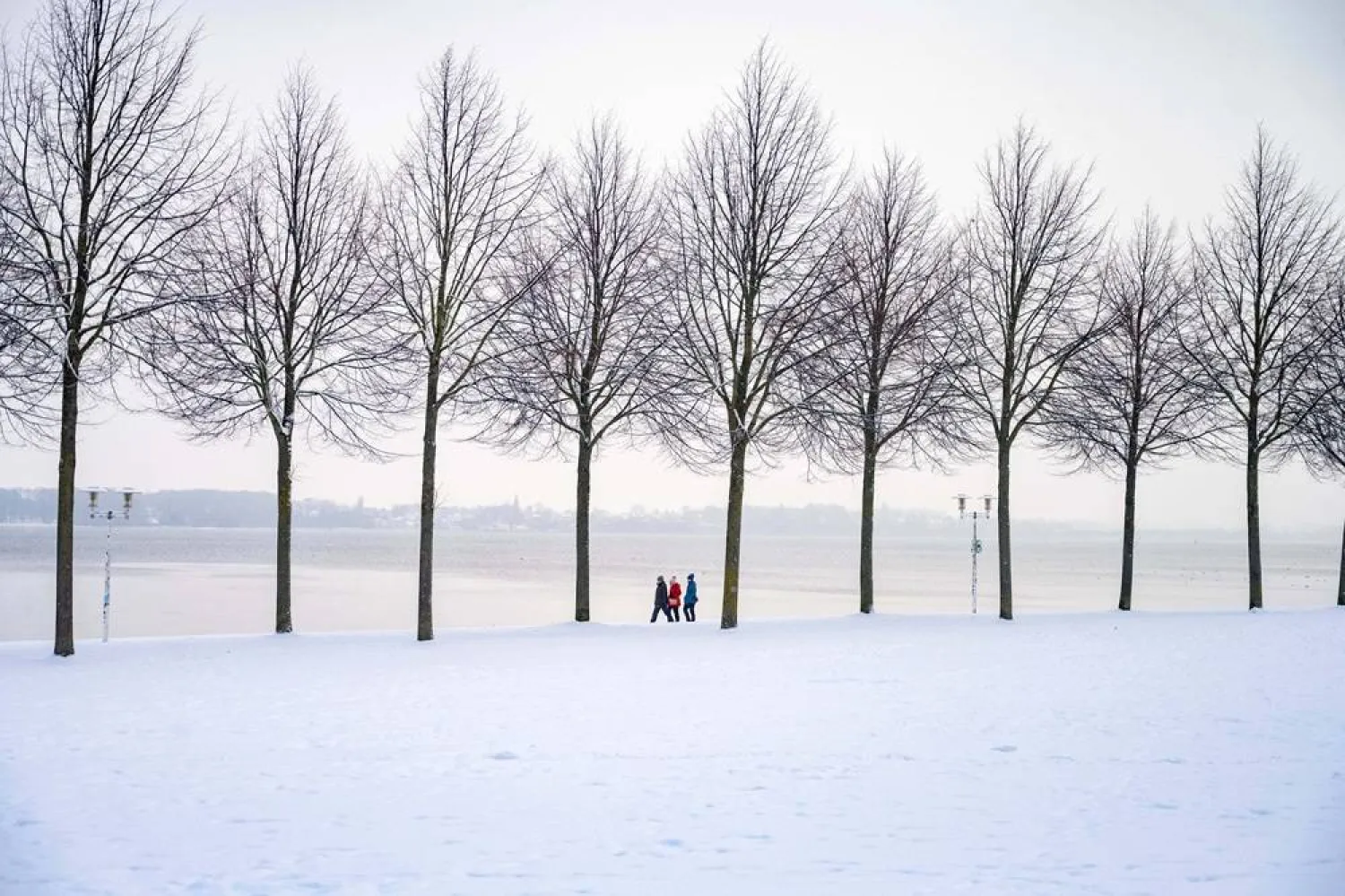  People walk along the Baltic Sea shore covered in a thick blanket of snow, in Stralsund, Germany, Tuesday, Jan. 6, 2026. (Stefan Sauer/dpa via AP) 