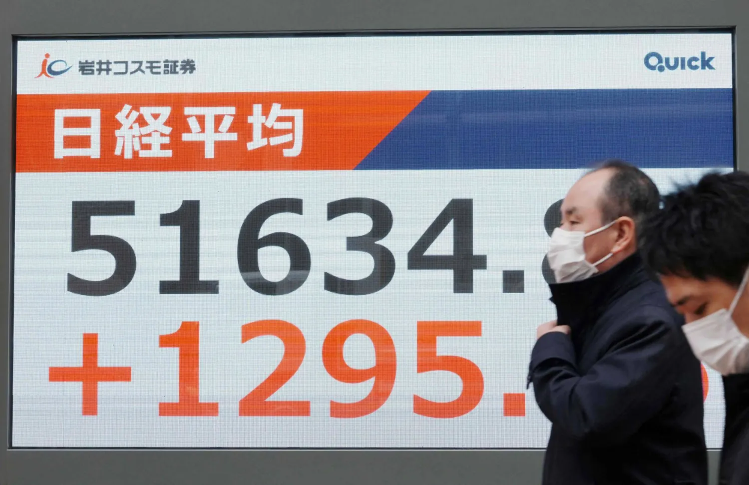 رجل يمر أمام شاشة إلكترونية تعرض حركة الأسهم في وسط العاصمة اليابانية طوكيو (أ.ف.ب)