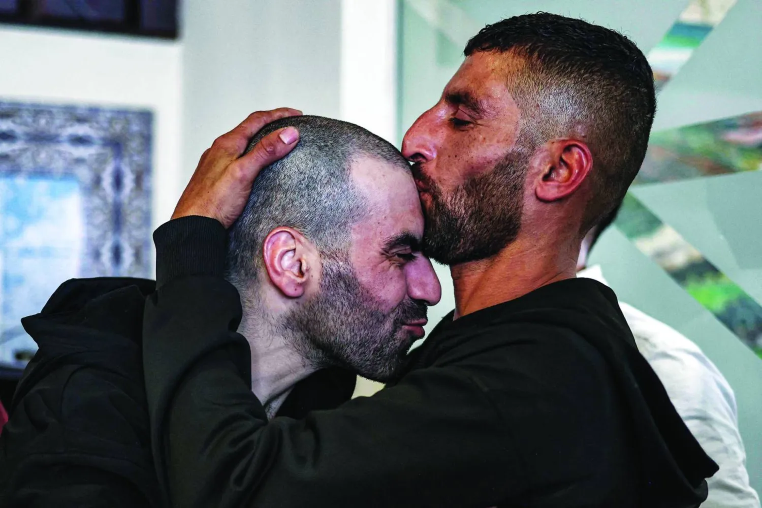 أسير فلسطيني محرَّر (يسار) يُقبِّله شقيقه لدى وصوله إلى رام الله قادماً من سجن عوفر الإسرائيلي (أ.ف.ب)