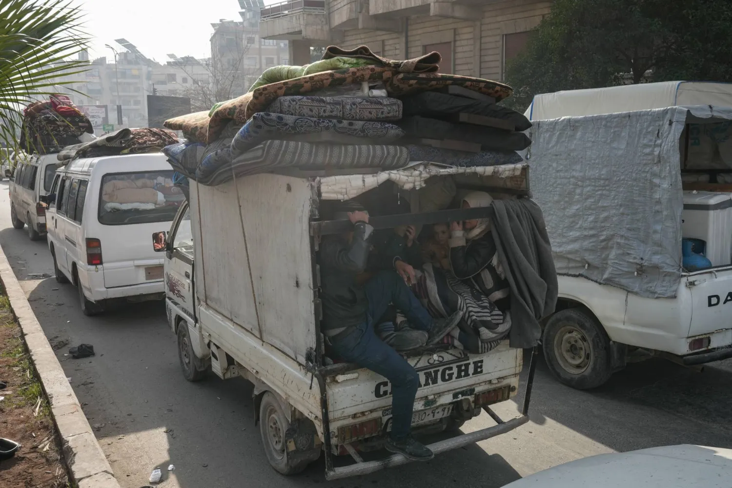 سوريون يستقلون شاحنة صغيرة في حلب أمس فيما يواصل آلاف المدنيين النزوح جراء الاشتباكات بين الجيش و"قسد" (إ.ب.أ)