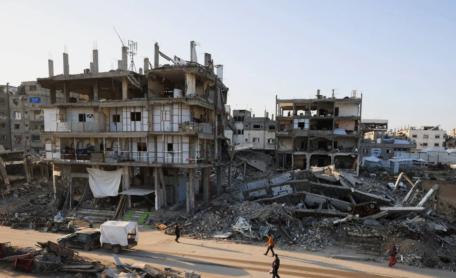 Palestinians walk past destroyed buildings in a neighborhood heavily damaged during the war, in Gaza City, January 5, 2026. (Reuters)