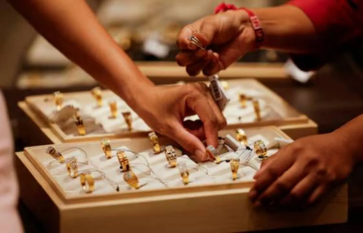 يعرض بائع خاتماً ذهبياً على زبائن داخل صالة عرض للمجوهرات في أحمد آباد بالهند (رويترز)