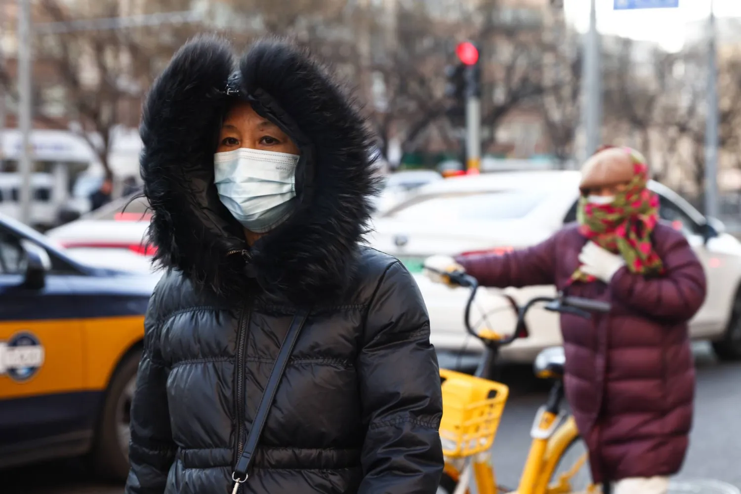 امرأة مسنة ترتدي كمامة تسير في أحد شوارع بكين (إ.ب.أ)