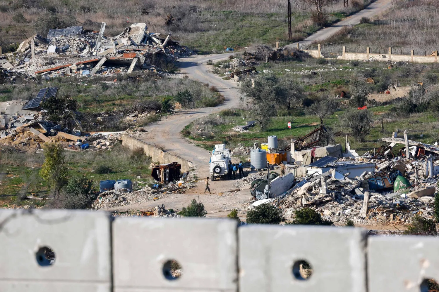 صورة مأخوذة من الجانب الإسرائيلي تظهر قوة من «اليونيفيل» بلبنان تقف مع جنود لبنانيين بجوار مبانٍ وسيارات دمَّرتها إسرائيل في قرية الضهيرة جنوب لبنان... 8 يناير (أ.ف.ب)