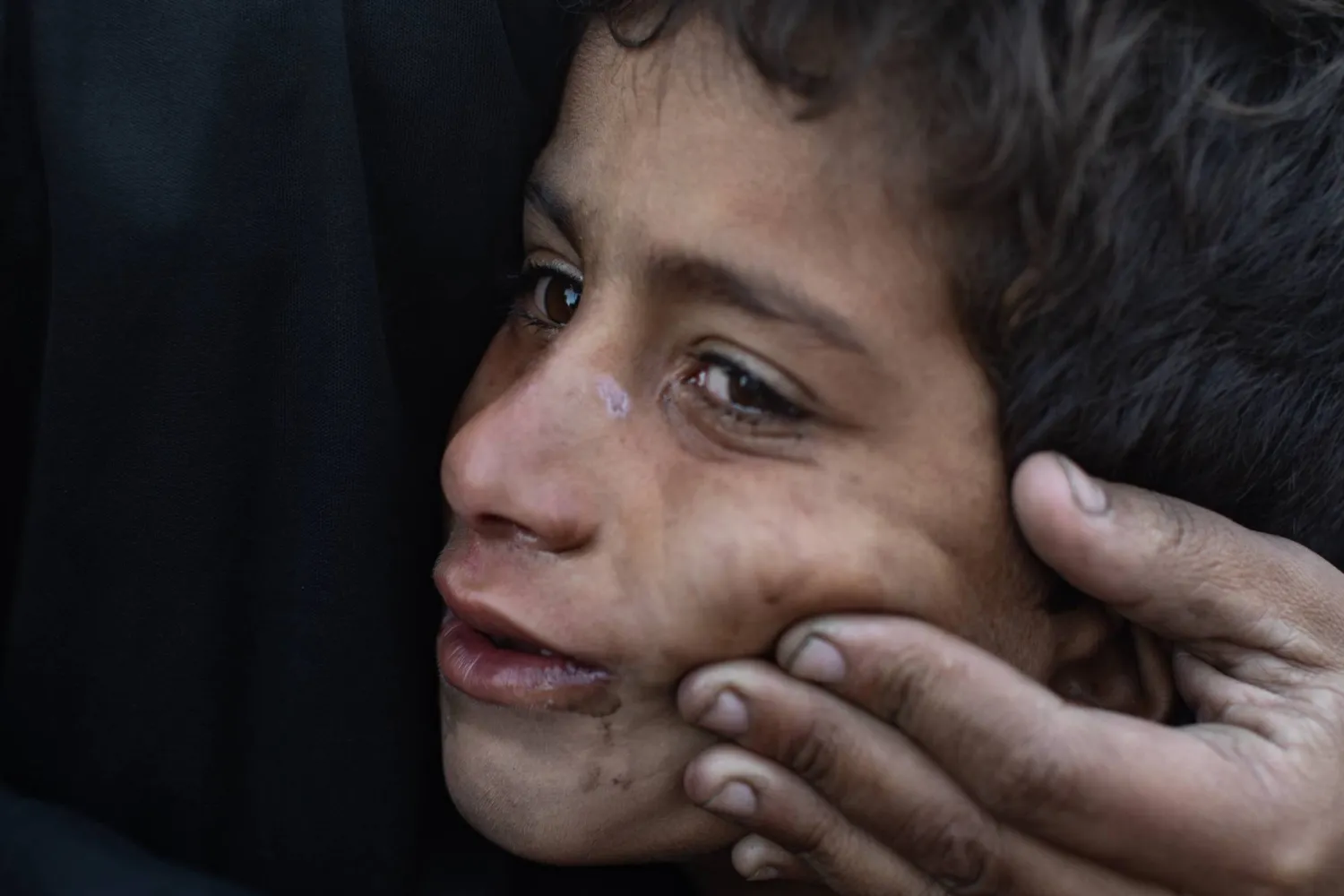 طفل فلسطيني يبكي بسبب البرد وظروف الحياة القاسية بعدما تضررت خيمة عائلته في خان يونس بجنوب قطاع غزة بسبب الرياح والأمطار الجمعة (إ.ب.أ)