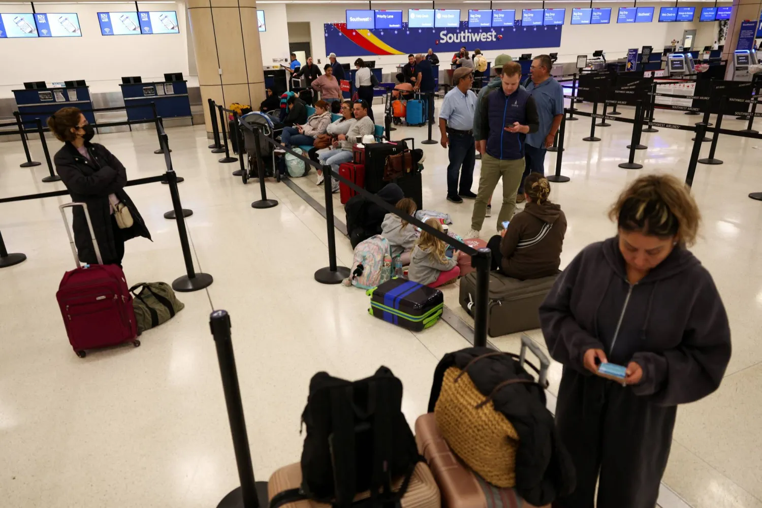 ينتظر المسافرون مع أمتعتهم بعد تأخير الرحلات الجوية (رويترز)