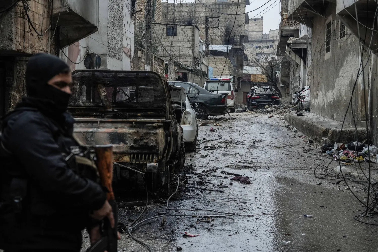 جندي سوري يقف أمام سيارة محترقة في حي الشيخ مقصود في حلب جراء الاشتباكات مع «قسد» (د.ب.أ)