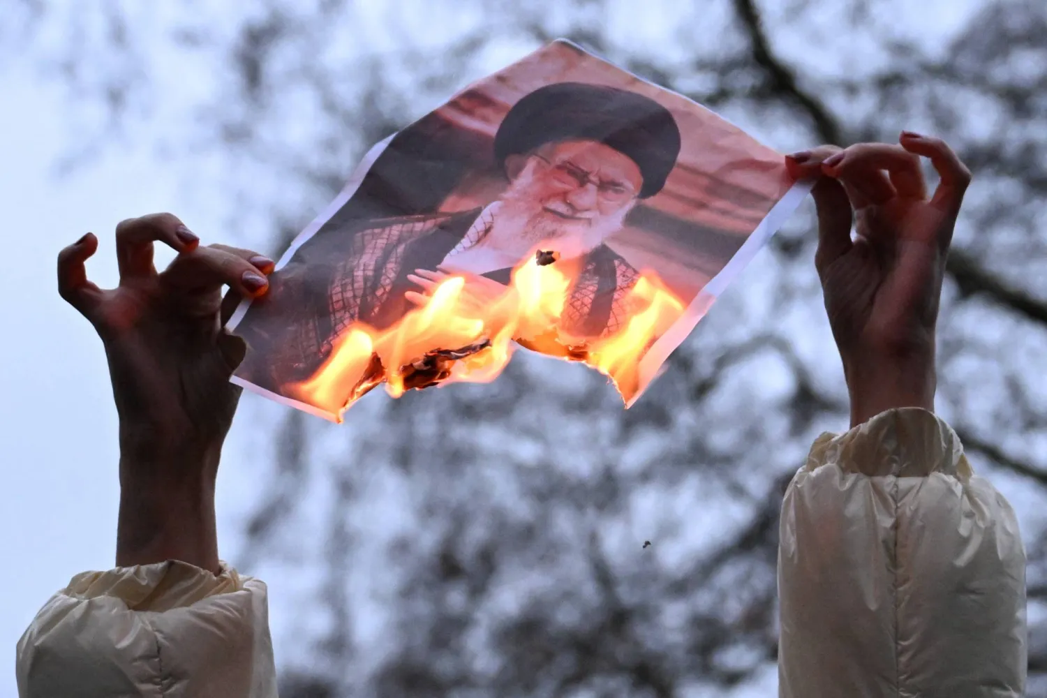 A demonstrator holds a burning photo of Iran's Supreme Leader Ali Khamenei, during a protest in support of the Iranian people outside Downing Street, as protests have spread across Iran since the end of December in response to soaring inflation and protesters demanding an end to clerical rule, in London, Britain, January 11, 2026. REUTERS/Chris J Ratcliffe