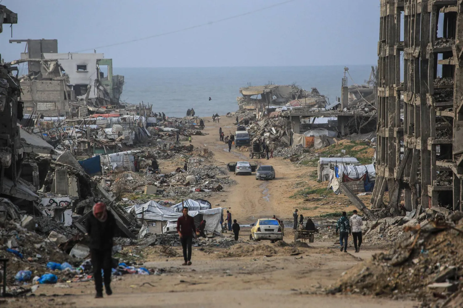 Palestinians walk along a road amid destroyed buildings in Jabalia, in the northern Gaza Strip, on January 10, 2026. (AFP)