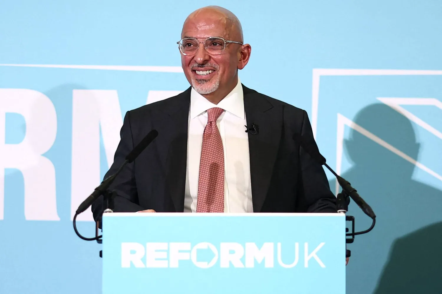 وزير الخزانة السابق من حزب «المحافظين» ناظم الزهاوي يتحدث على خشبة المسرح بعد أن تم الكشف عنه بصفته عضواً جديداً في حزب «الإصلاح» البريطاني بمؤتمر صحافي بلندن 12 يناير 2026 (أ.ف.ب)