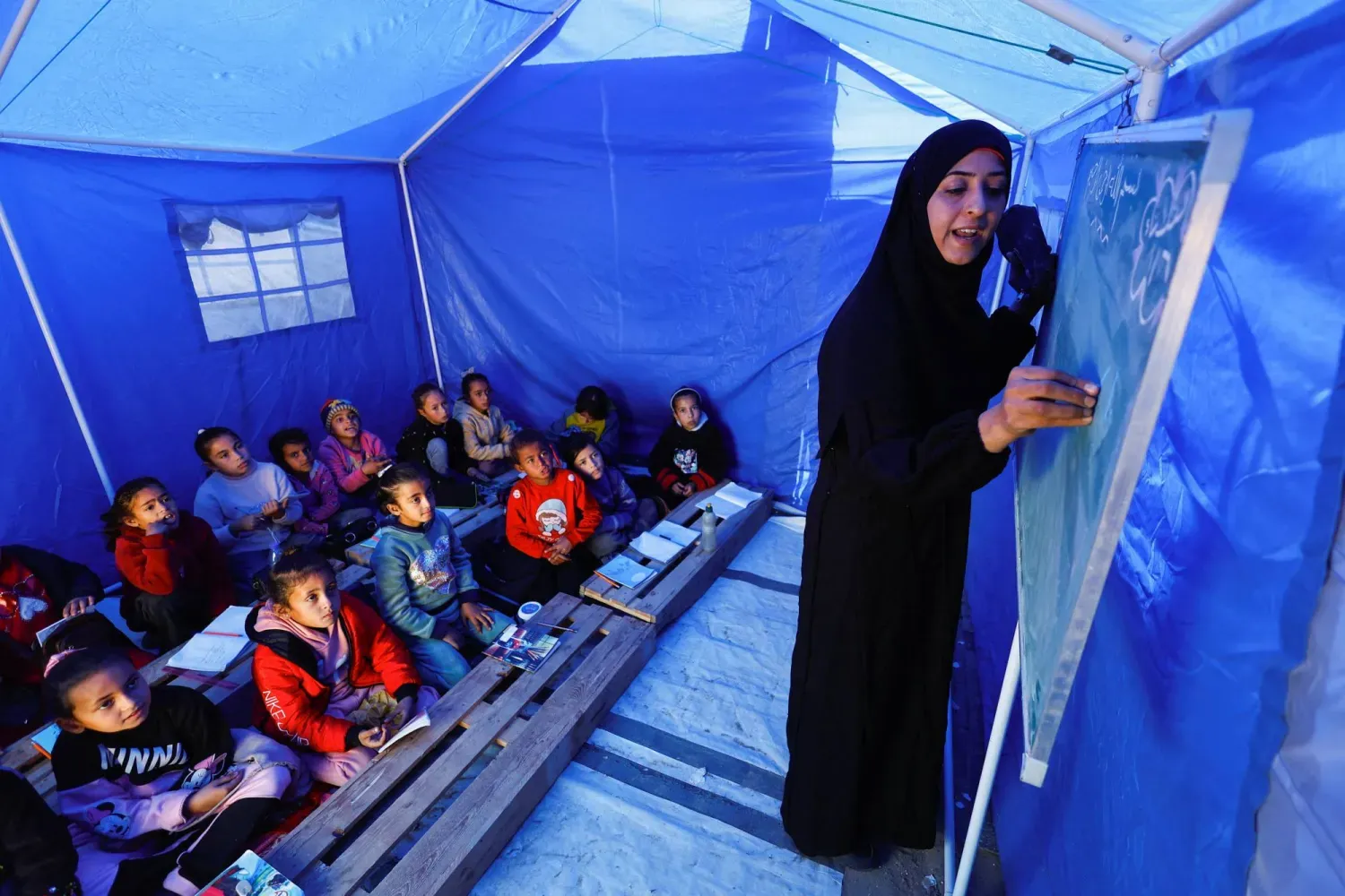 Yerinden edilmiş Filistinli çocuklar, Gazze'nin kuzeyindeki Beyt Lahiya'da, Hamas ve İsrail arasındaki sınır yakınlarında kurulan bir çadırda ders yapıyor (Reuters)