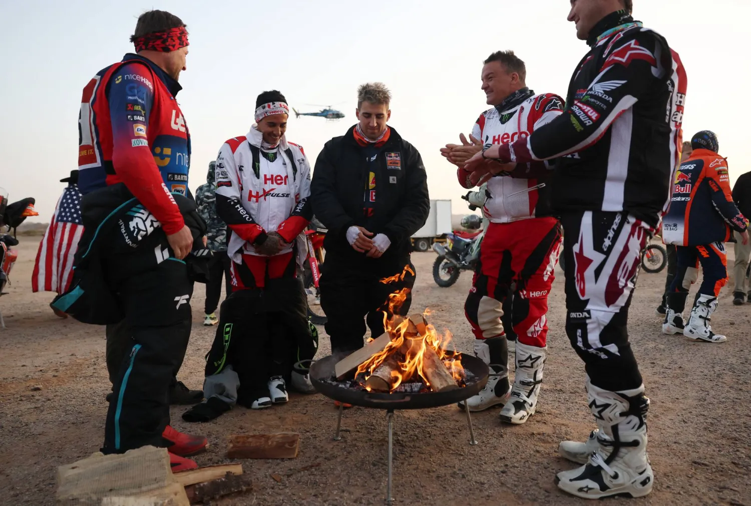 عدد من المتسابقين يتجمعون حول موقد نار بعد ختام المرحلة (رويترز)