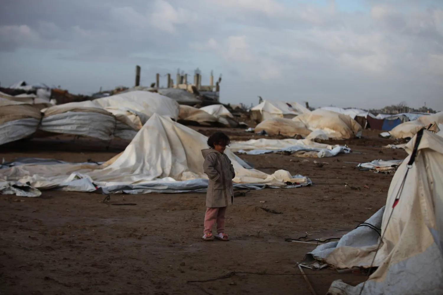 تقف فتاة فلسطينية بجوار خيام تضررت جراء الأمطار الغزيرة في الجزء الغربي من مخيم النصيرات للاجئين وسط قطاع غزة (د.ب.أ)