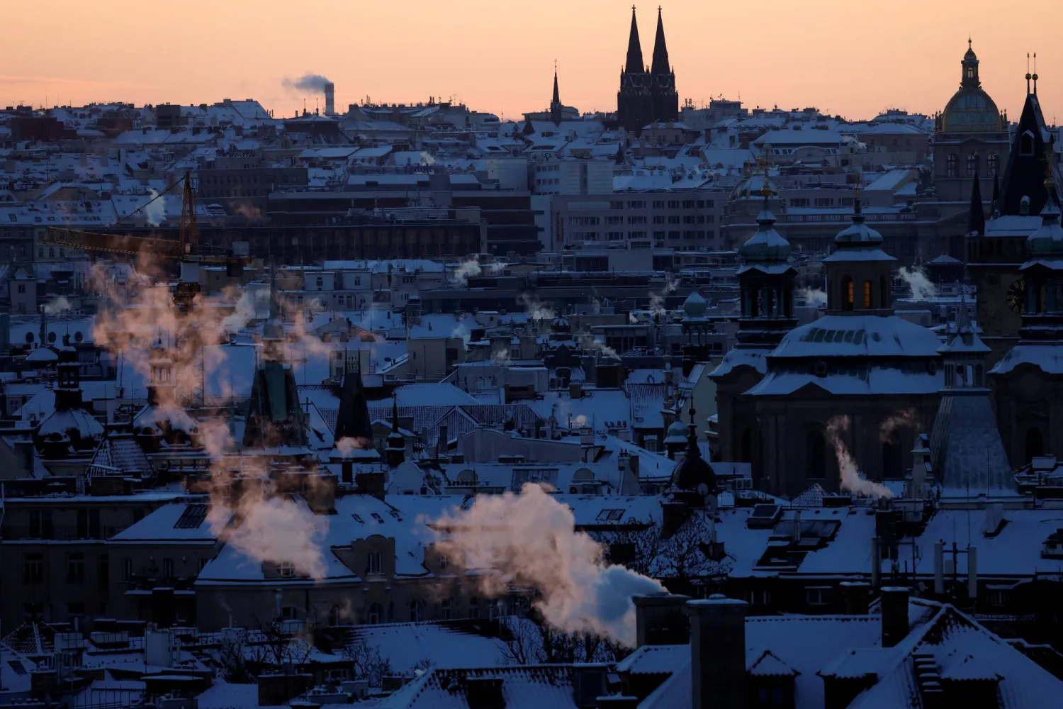 Smoke from chimneys billows over snow-covered rooftops during sunrise as freezing temperatures have hit the country, in Prague, Czech Republic, January 11, 2026. (Reuters)