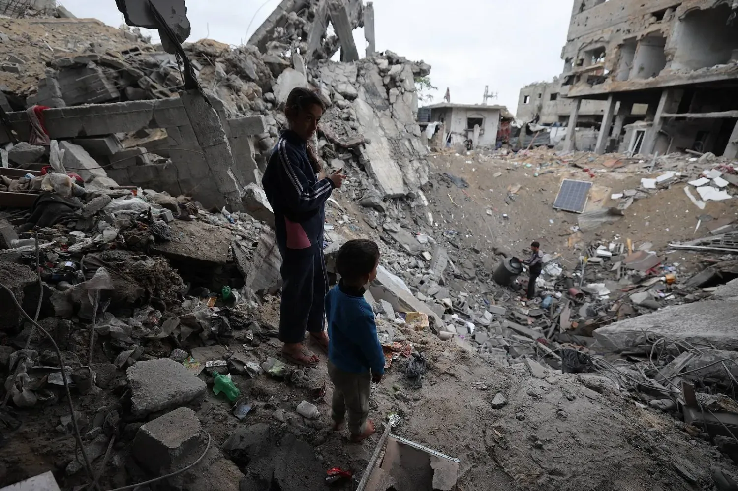 Filistinli çocuklar, Gazze Şeridi'nin merkezindeki Bureyc mülteci kampında bir çukurun yanında duruyor (AFP)