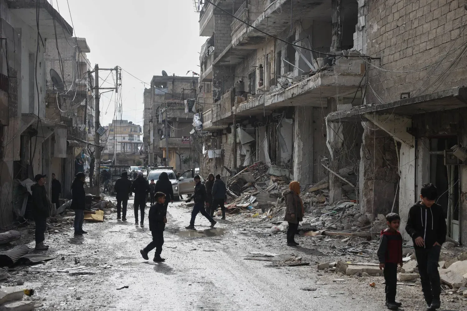 Suriye'de son çatışmaların ardından Halep'in Şeyh Maksud mahallesindeki binalarda meydana gelen hasarı inceleyen Suriyeliler (AP)