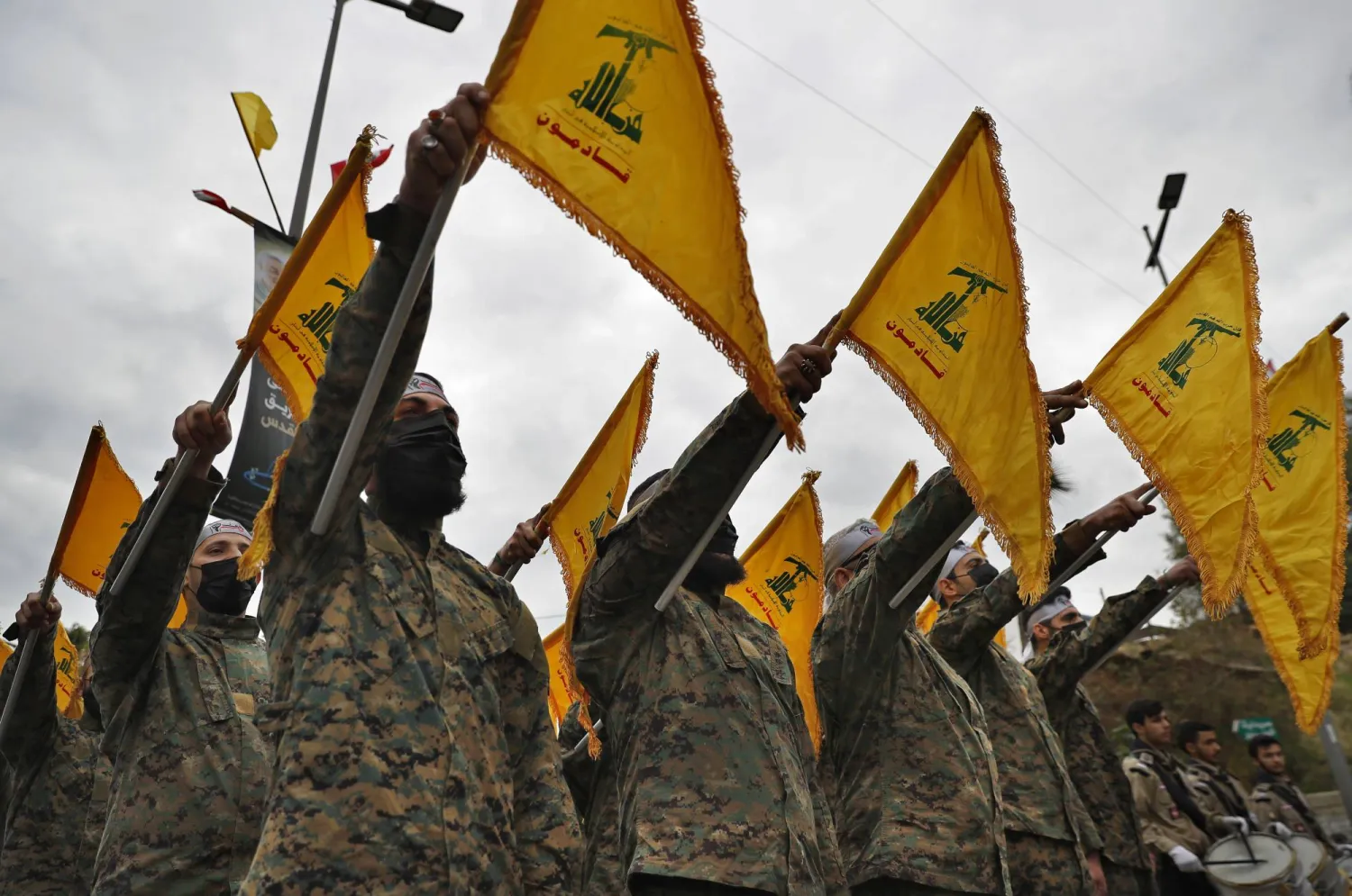 Hezbollah fighters hold their group's flag as they stand in front of a statue of Iranian General Qassem Soleimani and swear their oath of allegiance to him, during a ceremony to mark the second anniversary of his assassination, in the southern suburb of Beirut, Lebanon, Tuesday, Jan. 4, 2022. Soleimani was the head of Iran's Quds force who was killed by a U.S. drone in Baghdad in January 2020. (AP Photo/Hussein Malla)