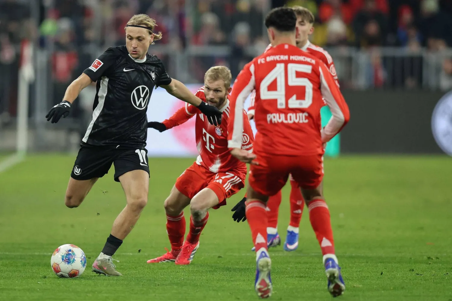 Wolfsburg's Croatian midfielder #10 Lovro Majer (L) and Bayern Munich's Austrian midfielder #27 Konrad Laimer vie for the ball during the German first division Bundesliga football match between FC Bayern Munich and VfL Wolfsburg in Munich, southern Germany, on January 11, 2026. (AFP)