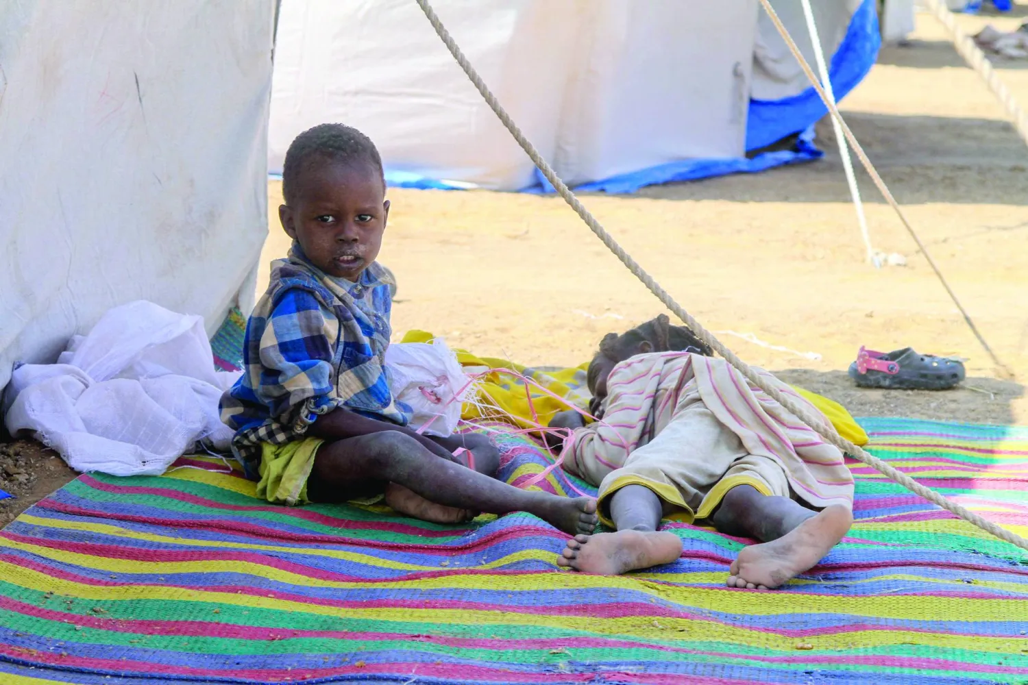 طفلان من الفاشر يستريحان في مخيم للنازحين السودانيين ببلدة الدبة الشمالية (أ.ف.ب)