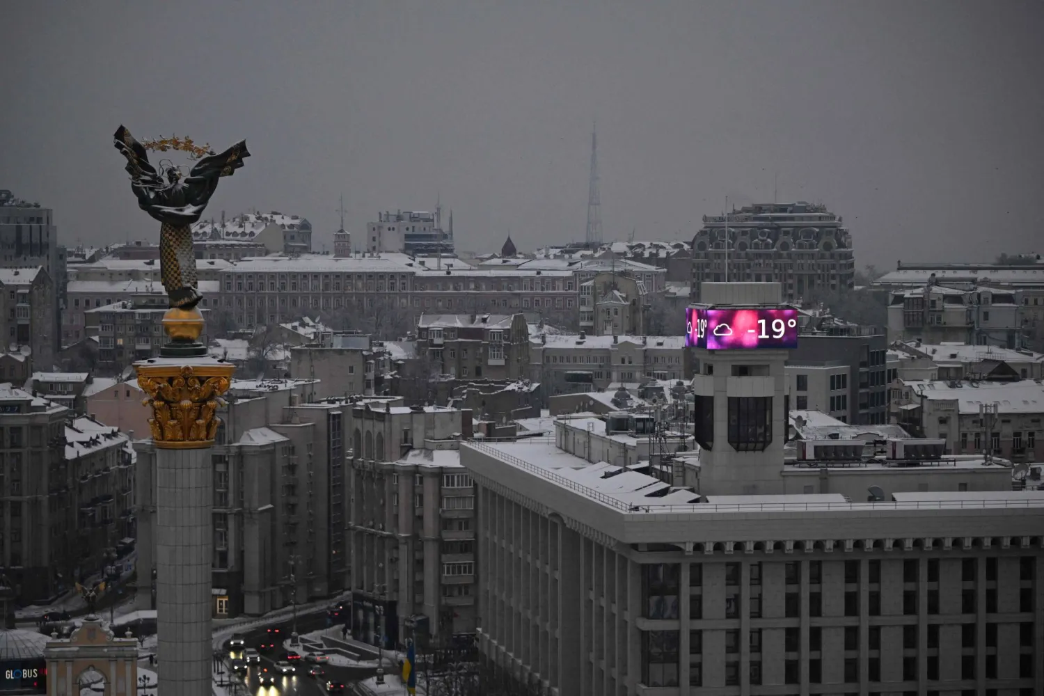 TOPSHOT - Cars drive along the Independence Square as a big screen on a building displays a temperature of -19 degrees Celsius in Kyiv on January 15, 2026, amid the Russian invasion of Ukraine. (Photo by Sergei GAPON / AFP)